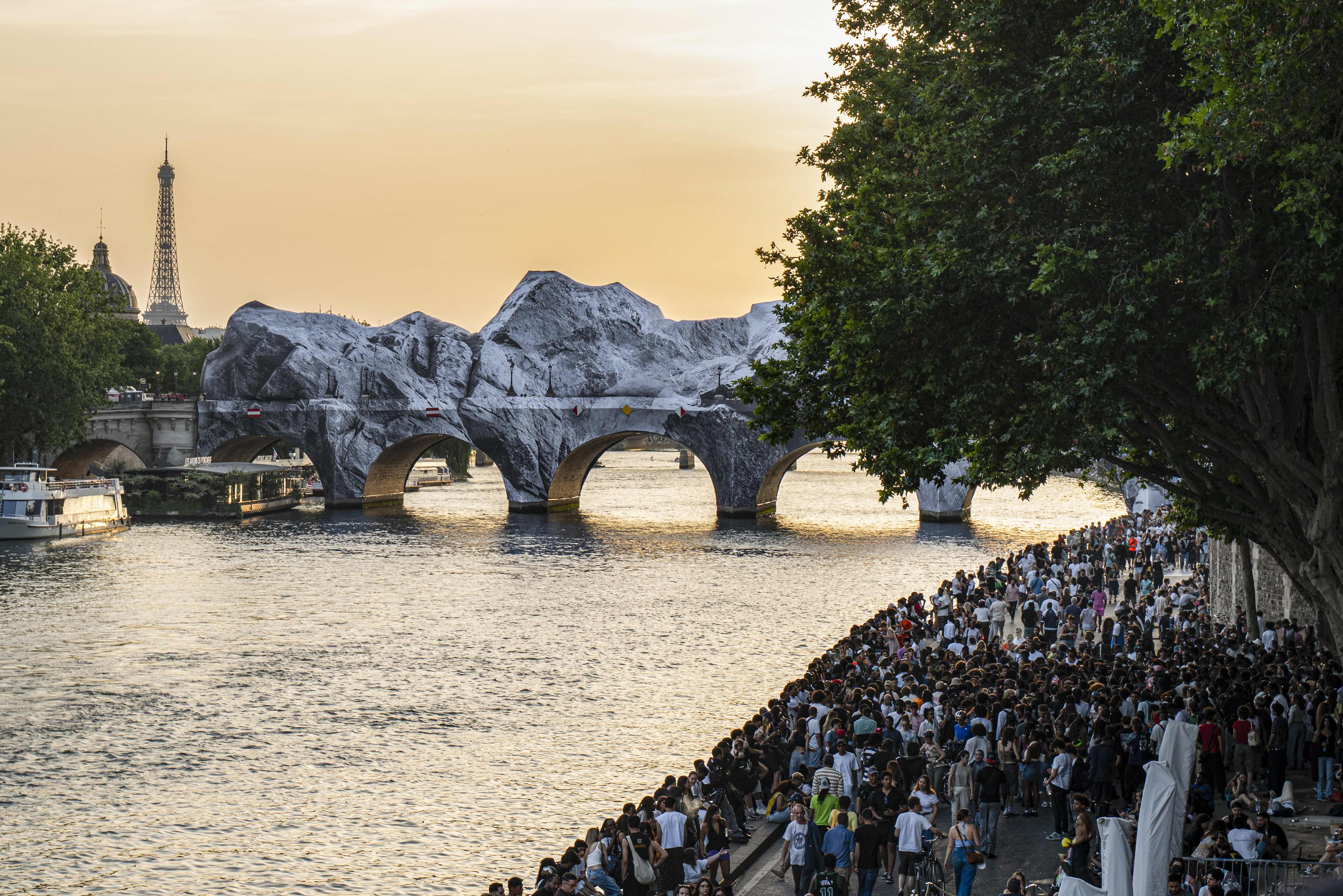 La Caverne du Pont Neuf enveloppé comme un paysage rocheux au-dessus de la Seine au coucher du soleil, avec la foule sur les quais